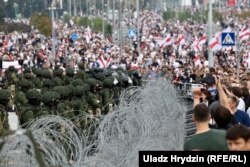 Колючая проволока между военными, окружившими стелу "Минск – город-герой", и демонстрантами. 23 августа
