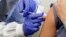 U.K. -- A subject receives a shot in the first-stage safety study clinical trial of a potential vaccine by Moderna for COVID-19, the disease caused by the new coronavirus, at the Kaiser Permanente Washington Health Research Institute in Seattle, March 16,