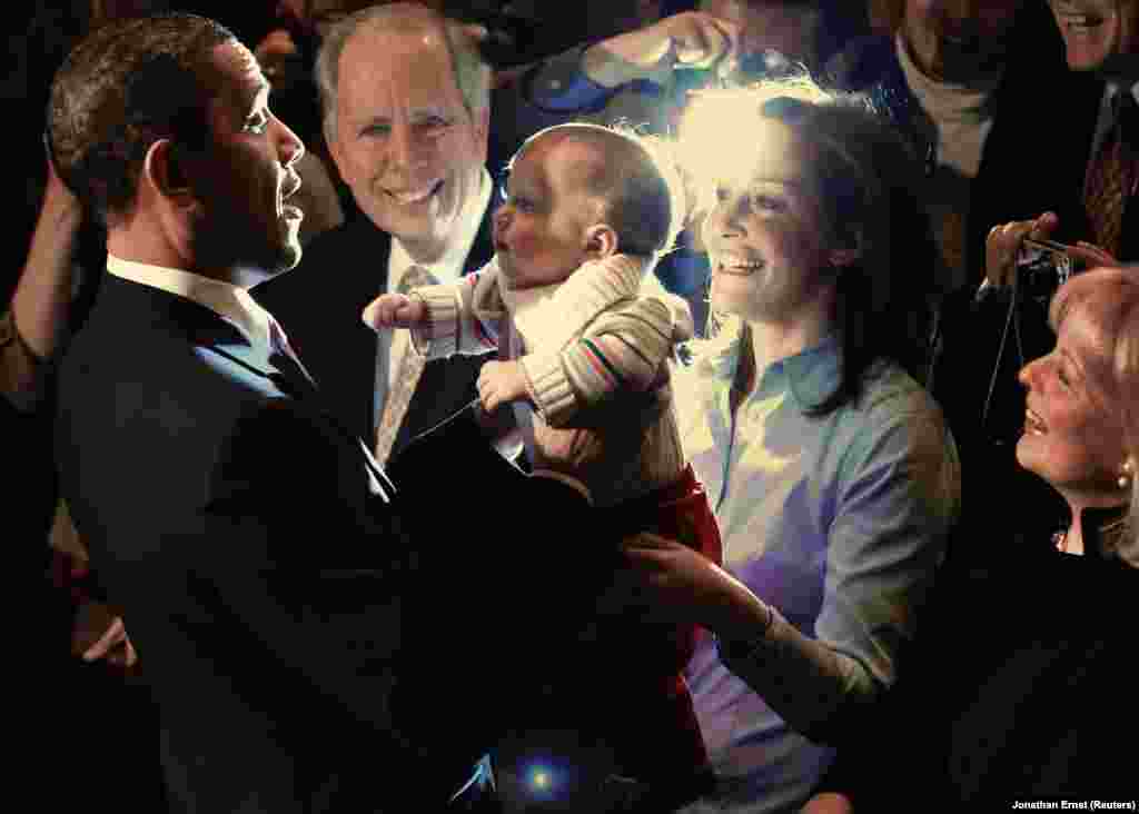 Президент держит на руках ребенка своей сторонницы в Александрии, штат Вирджиния, 30 марта 2010 года. Фото было сделано вскоре после того, как вступил в силу закон о доступном здравоохранении, широко известный как Obamacare. Закон расширил доступ к медицинскому обслуживанию для порядка 20 миллионов граждан США, которые ранее не имели медицинской страховки.