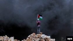 Palestine - Palestinian protester waves Palestine flag during clashes over the Jewish settlement of Qadomem at Kofr Qadom village, near West Bank city of Nablus, 13 June 2014