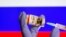RUSSIA -- A woman holds a small bottle labeled with a "Coronavirus COVID-19 Vaccine" sticker and a medical syringe in front of displayed Russia flag - generic