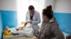 Дмитрий Розумий осматривает ребенка. 51-летний семейный доктор раньше работал хирургом-онкологом, но ушел, заявив, что сокращение бюджета повышает смертность