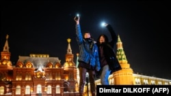 Young people near Moscow's Red Square turn on the flashlights of their cell phones to support jailed opposition politician Aleksei Navalny on February 14, 2021.