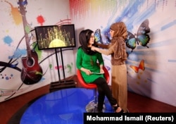 Khatira Ahmadi, a producer at Kabul's all-women Zan TV station, adjusts the headscarf of a presenter before recording on May 8, 2017.