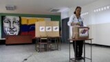 Venezuela -- With an image of the late Venezuelan President Hugo Chavez behind her a Venezuelan citizen casts her vote at a polling station during the presidential election in Caracas, Venezuela, May 20, 2018