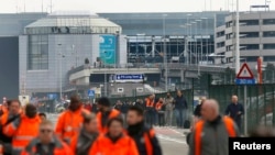Люди покидают здание аэропорта в Брюсселе, где утром 22 марта 2016 произошли два взрыва 