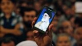 Iran -- An Iranian man holds his mobile phone showing a picture of Iranian supreme leader Ayatollah Ali Khamenei as he attends the ceremonies on the occasion of the 26th death anniversary of Ayatollah Ruhollah Khomeini in southern Tehran, June 3, 2015