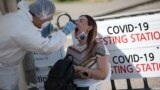 Kazakhstan - A health worker takes a swab from a woman at a mobile testing station for the coronavirus disease (COVID-19) in Almaty