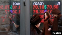 Прохожие в Москве рядом с электронным табло с курсами покупки и продажи валют. 16 декабря 2015 года.