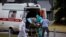 RUSSIA -- Medics escort a woman into a hospital where patients infected with the COVID-19 novel coronavirus are being treated in the settlement of Kommunarka outside Moscow, June 30, 2021