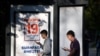 RUSSIA -- Young men use their smartphones walking past a poster announcing the upcoming Russian parliamentary election in Moscow, August 31, 2021