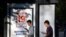 RUSSIA -- Young men use their smartphones walking past a poster announcing the upcoming Russian parliamentary election in Moscow, August 31, 2021