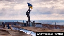 Украинские солдаты устанавливают флаг в освобожденном поселке Высокополье Херсонской области, 4 сентября 2022 года