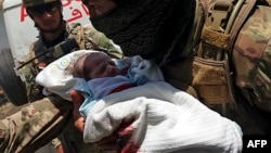 Служащий правительственных войск Афганистана с раненым новорожденным после освобождения госпиталя от захвата