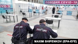 Полицейские заполняют документы на вакцинацию "Спутником V". Москва, Гостиный двор, июль 2021 года. Фото: EPA-EFE