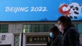 China -- People walk past a banner with a sign of Beijing 2022 Winter Olympic Games, 100 days ahead of the opening of the event, in Beijing, China October 27, 2021. REUTERS/Tingshu Wang
