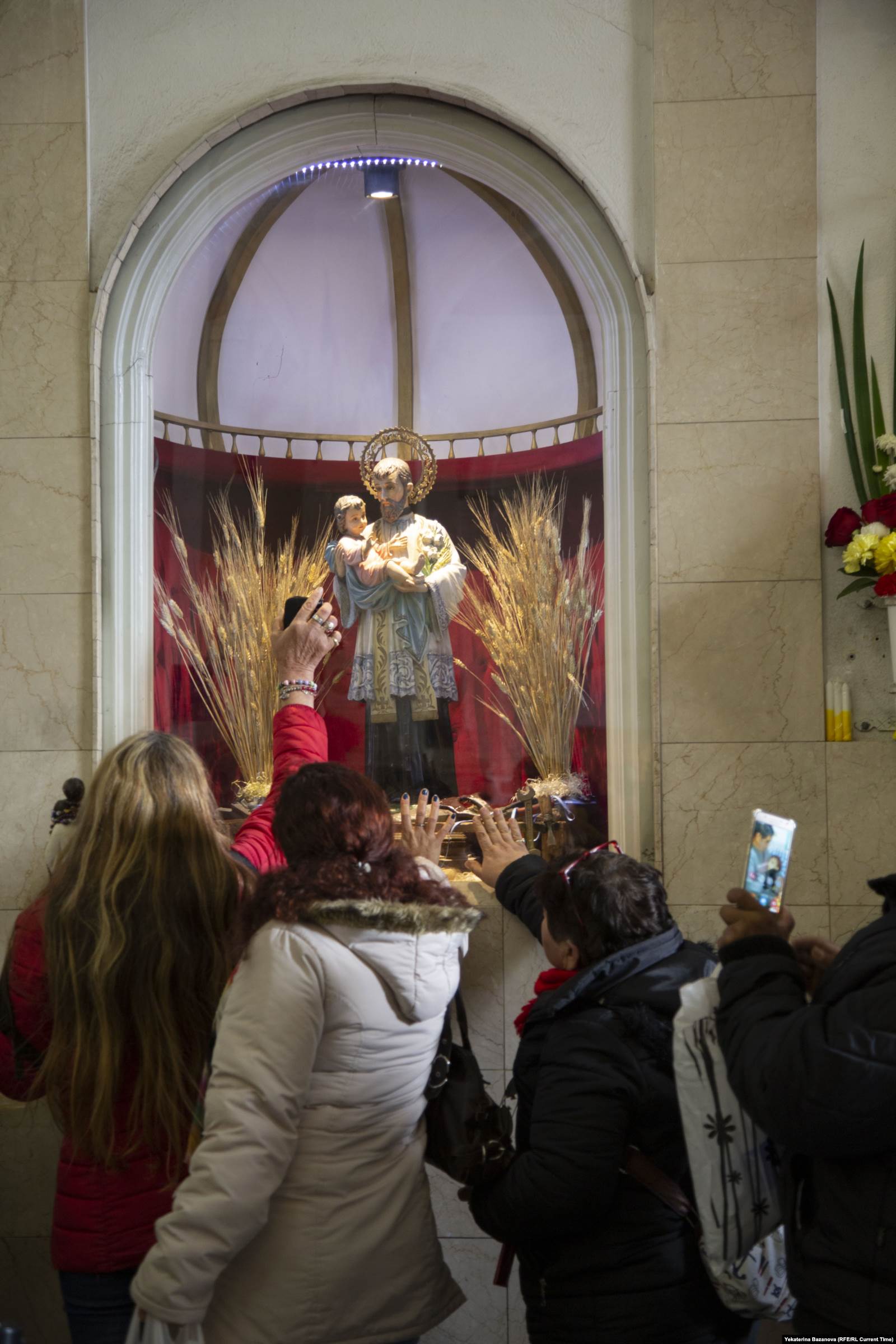 Паломники прикладывают руки и телефоны с фотографиями близких к образу Святого Каэтано. Фото: Франко Ловисоло