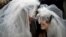 France -- Two women wearing a wedding veil, stare at each other in front of Notre-Dame Cathedral, in Paris during a demonstration for the legalisation of gay marriage and LGBT (lesbian, gay, bisexual, and transgender) parenting, 16Dec2012