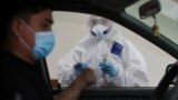 Kazakhstan - A health worker approaches a car driver at a mobile testing station for the coronavirus disease (COVID-19) in Almaty, Kazakhstan June 17, 2020. REUTERS/Pavel Mikheyev