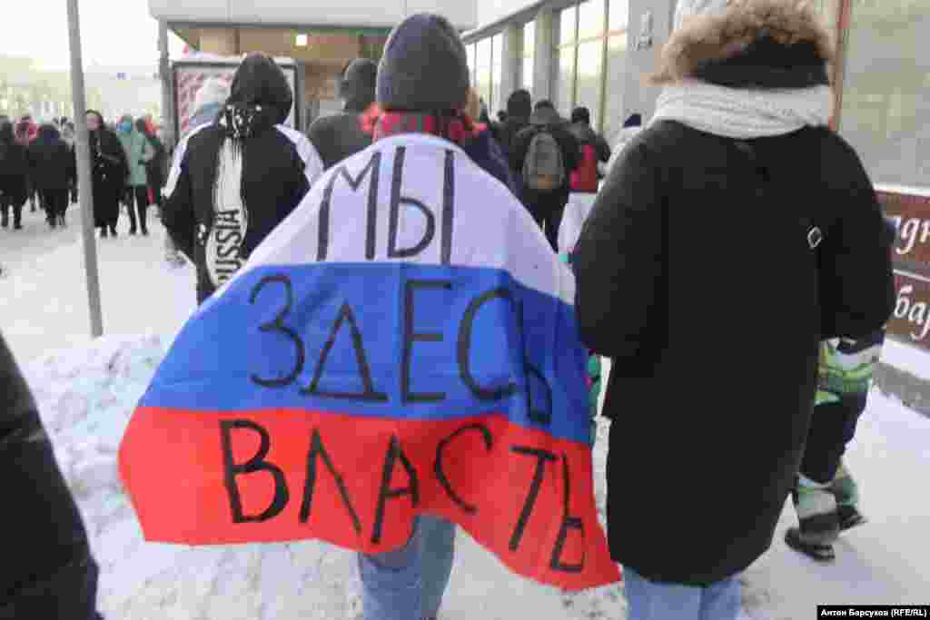 A protester in Novosibirsk wears a Russian flag with the slogan &quot;We&#39;re in charge here.&quot;&nbsp;