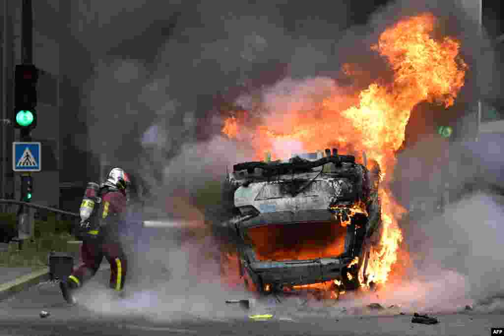 Пожарный тушит машину, подожженную во время беспорядков,&nbsp;29 июня, 2023 года