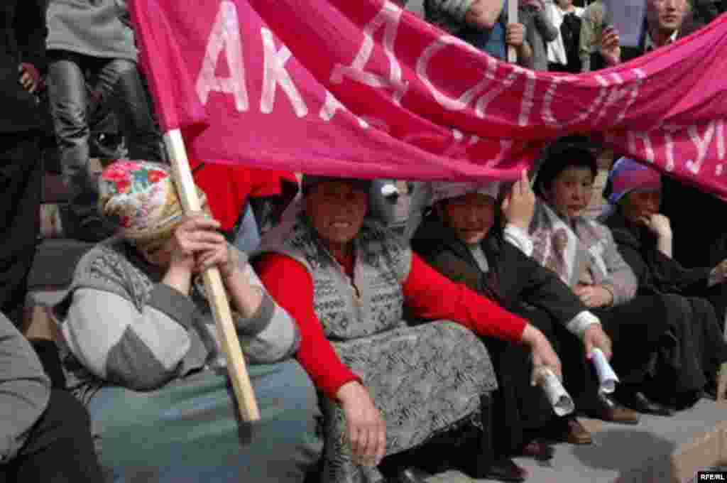 Участницы акции протеста держат плакат, призывающий Аскара Акаева уйти в отставку