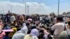 Afghan people gather along a road as they wait to board a U S military aircraft to leave the country, at a military airport in Kabul on August 20, 2021 days after Taliban's military takeover of Afghanistan. (Photo by Wakil KOHSAR / AFP)