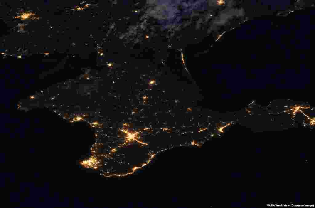 На снимках Крыма, аннексированного Россией, также заметно сокращение ночного освещения в связи с продолжающимися украинскими атаками беспилотников на объекты энергосистемы полуострова. Снимки сделаны 8 июля 2021 года и 3 июля 2026 года.ода