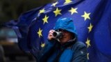 U.K. -- A man takes photographs of pro EU protestors' flags opposite the Houses of Parliament in London, Thursday, April 4, 2019. 
