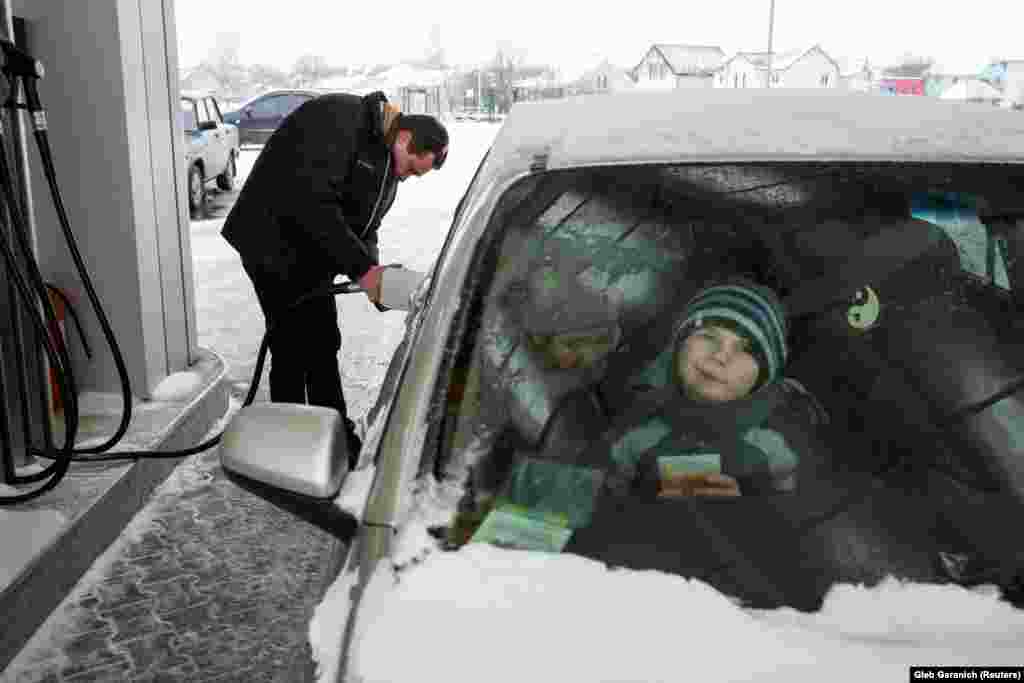 Дмитрий Розумий заправляет машину, дети ждут внутри