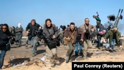 Репортеры New York Times, Getty Images и Reuters бегут в укрытие во время бомбардировки правительственных войск Ливии вблизи нефтяного завода Рас эль-Ануф в марте 2011 года
