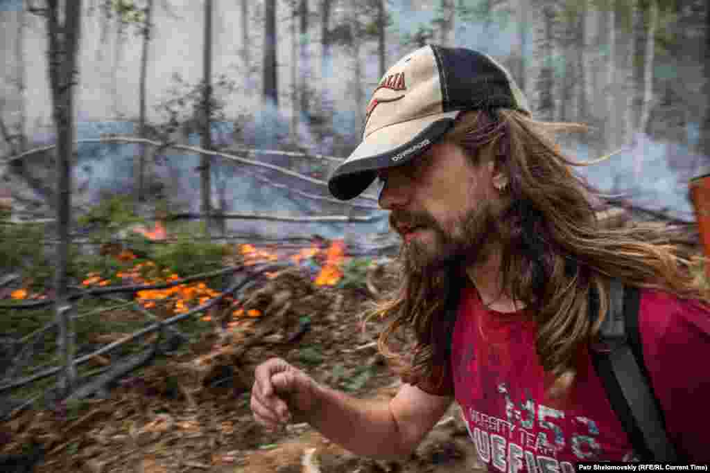 Огонь распространяется через сухой лес по всему острову На фото - волонтер Антон Волков проходит рядом с огнем