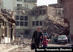 Жители Приштины, столицы Косово, идут среди руин после авиаударов войск НАТО 7 апреля 1999 года