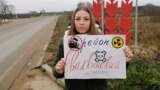 Ангелина Иванова с плакатом против свалки на фоне стелы с названием Палкинского района Псковской области