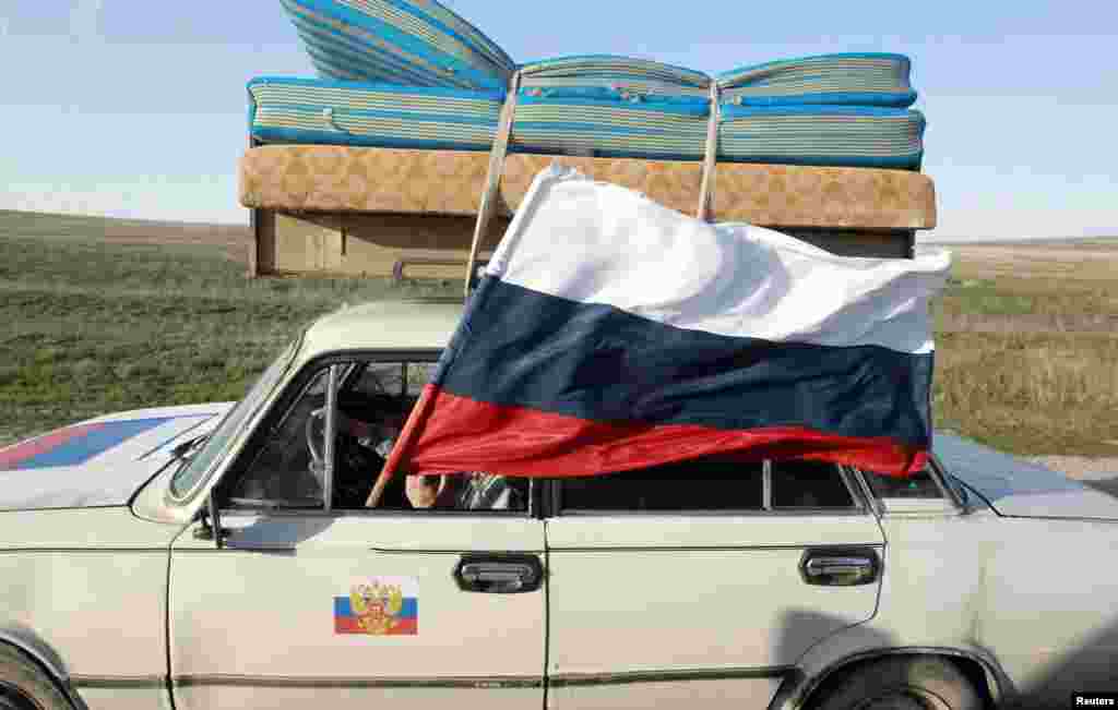Автомобиль с развивающимся флагом России проезжает около портового города Феодосия после аннексии РФ Крымского полуострова. (Shamil Zhumatov, Reuters)