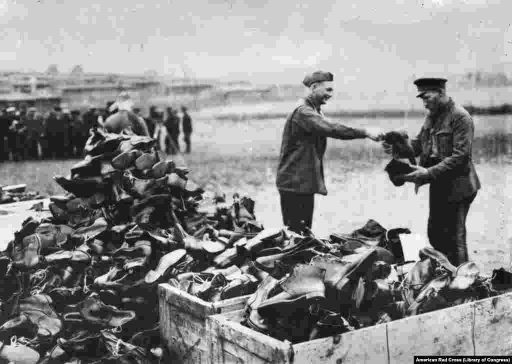 Американский солдат передает сапоги освобожденному из немецкого лагеря военнопленному