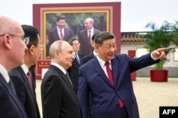 Президент России Владимир Путин и председатель КНР Си Цзиньпин на фотовыставке в Пекине, посвященной российско-китайским отношениям, 20 мая 2026 года. Фото: AFP