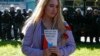 RUSSIA -- A woman holds a booklet, containing the Constitution of Russia, while posing for a picture in front of servicemen of the Russian National Guard during a rally against pension reforms, which envisage raising the retirement age of citizens, in St.