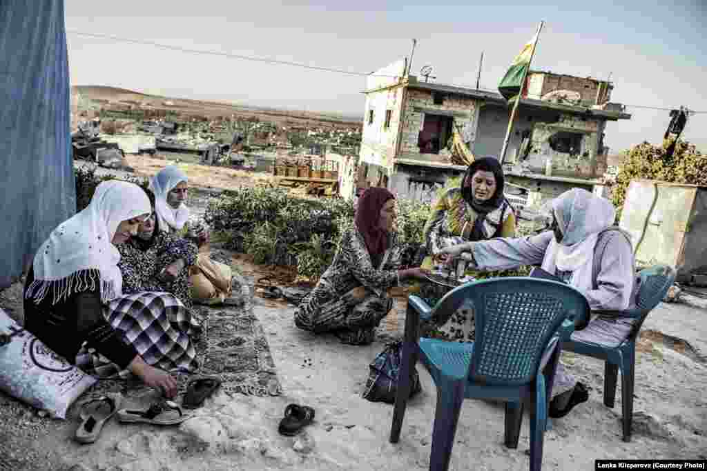 Женщины пьют чай на холме в Кобани. Они живут в палаточном городке рядом с разрушенными домами