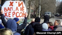 Протестующие против оккупации жители Херсона стоят перед колонной российских военных, март 2022 года. Фото: AP
