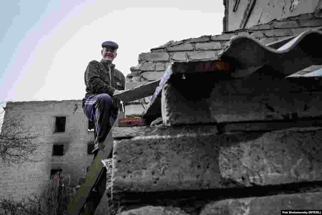 Мужчина чинит крышу своего поврежденного дома в Дебальцево