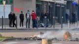 FRANCE -- People stand near a torn down street sign and a fire in the street in the Gresilles area of Dijon, eastern France, on June 15, 2020, as new tensions flared in the city after it was rocked by a weekend of unrest blamed on Chechens seeking vengean