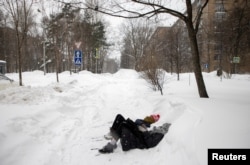 Девушки лежат в сугробе во время снегопада. 13 февраля 2021 года. Фото: Reuters