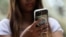 A teenager poses holding a mobile phone as law banning social media for users under 16 in Australia takes effect, in Sydney