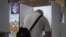 RUSSIA -- A man wearing a protective face mask and gloves prepares to cast his ballot during early voting in a referendum on amendments to the Russian Constitution next to a portrait of Russian President Vladimir Putin at a polling station in Moscow, June