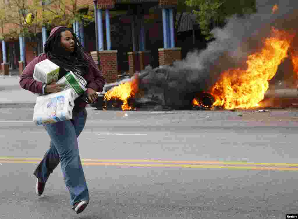 Женщина с товарами из разграбленного во время беспорядков магазина в Балтиморе&nbsp;