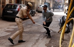Полицейский бьет палкой нарушителя карантина на улице Нью-Дели, Индия. 25 марта 2020 года. Фото: Reuters