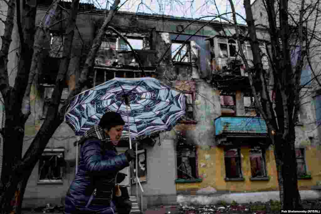 Женщина проходит мимо разрушенного дома в Дебальцево​