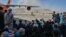 AFGHANISTAN -- Afghan people sit as they wait to leave the Kabul airport in Kabul, August 16, 2021
