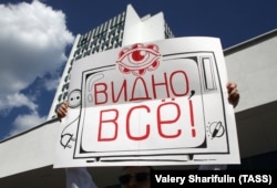 At a rally by striking workers outside Belarus' National State Television and Radio, a participant holds a poster that reads "Everything is seen!"